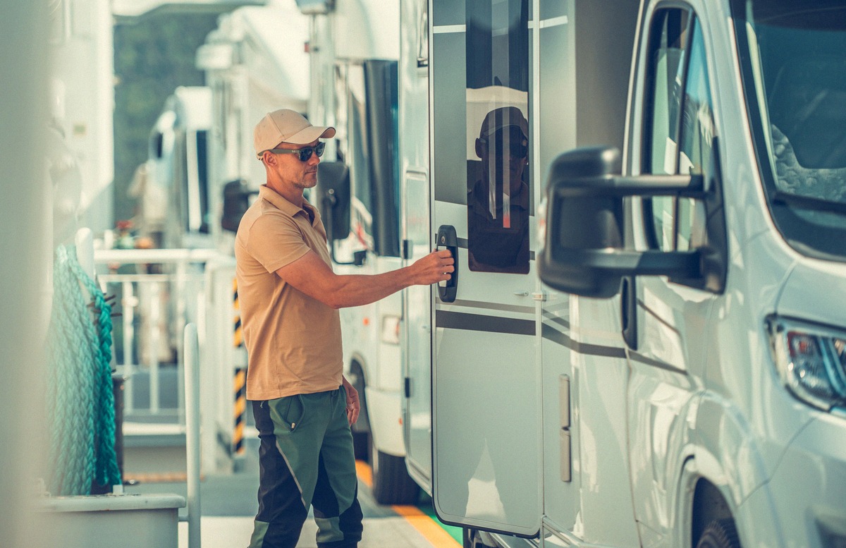 Motorhomes parked close together on the vehicle deck of a ferry, a traveller opening the door of a motorhome